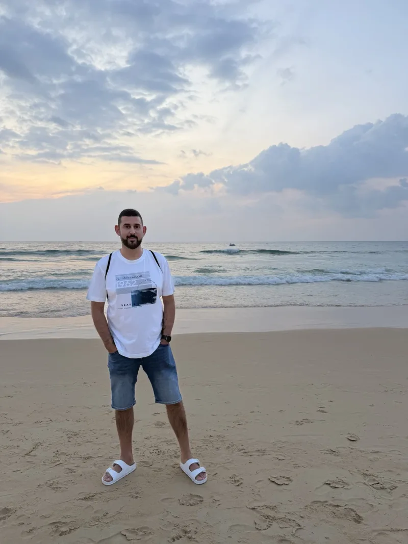Andreas steht am Strand vor dem Meer im Abendlicht.